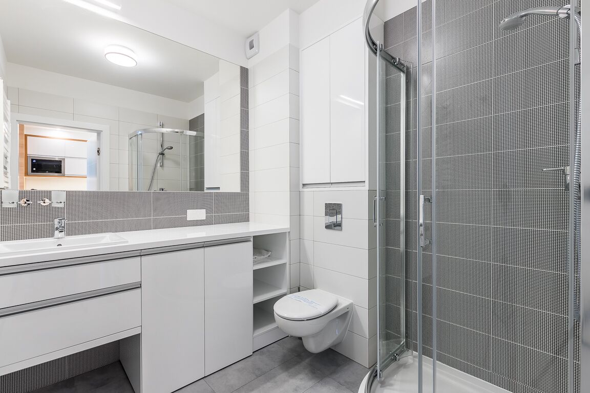 Une salle de bain moderne avec une douche à parois de verre, un lavabo blanc et des toilettes.