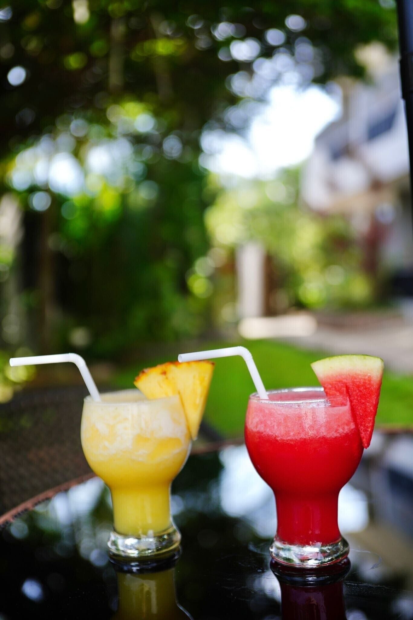 Tres bebidas con pajitas sobre una mesa, con un fondo exterior desenfocado.