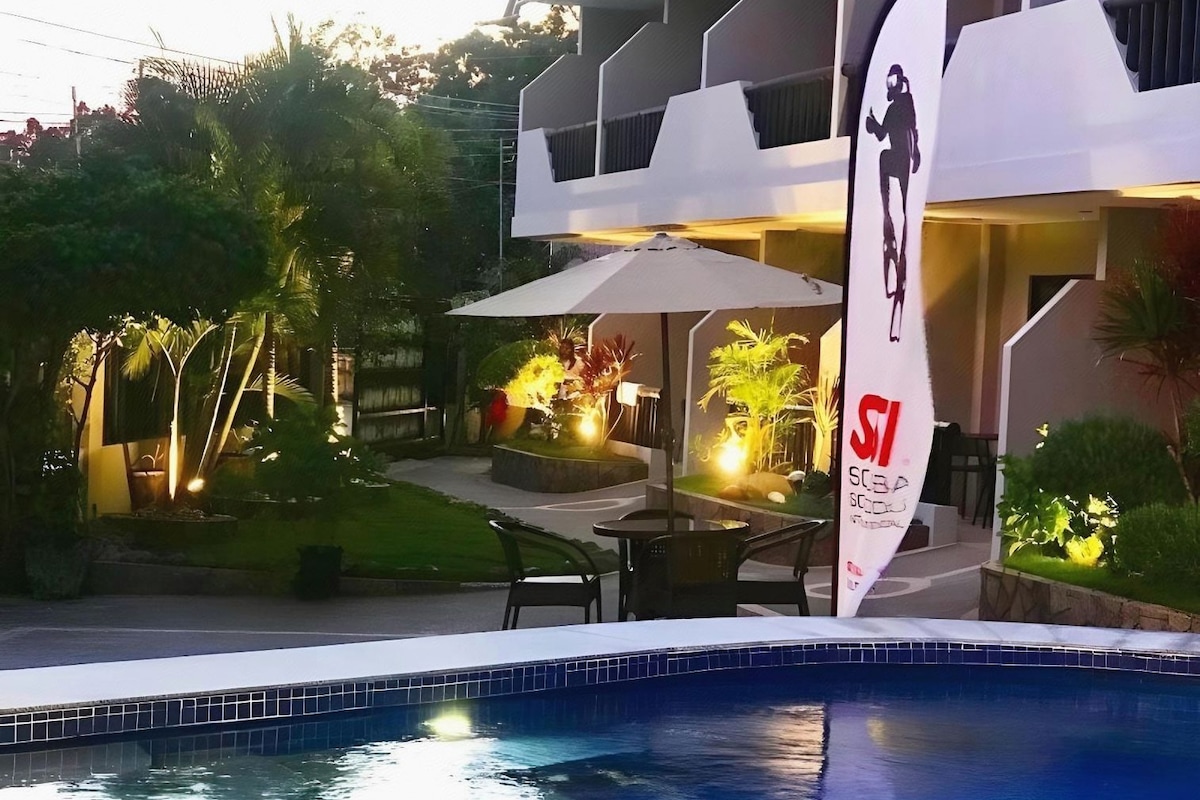 Un espace piscine d’hôtel aménagé avec un coin repas et un drapeau.