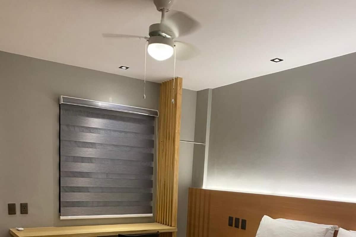 Un dormitorio con cama, escritorio y ventilador de techo.