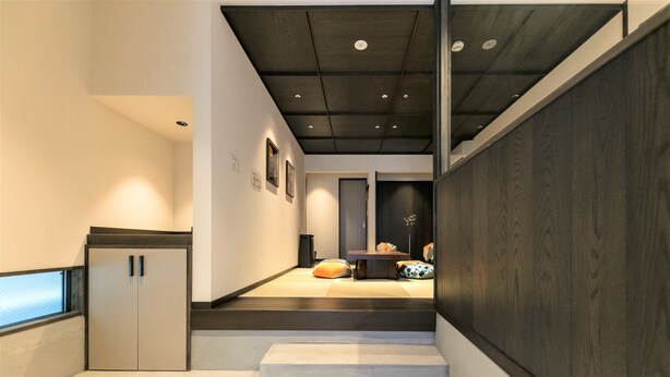 Ein modernes Interieur mit einer Treppe, einer kleinen Sitzecke und Blick durch ein Fenster.