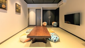 Ein modernes Zimmer mit Holztisch, gepolsterten Sitzgelegenheiten, einem Flachbildfernseher und Bildern an den Wänden.