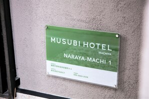 Señal del Hotel Musubi en Naraya-Machi, con la dirección y número de contacto.