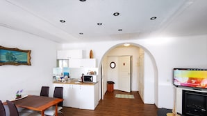 A compact living space with a dining area, kitchenette, and a TV in the living room. - Meridian Apartments (Klaipeda)