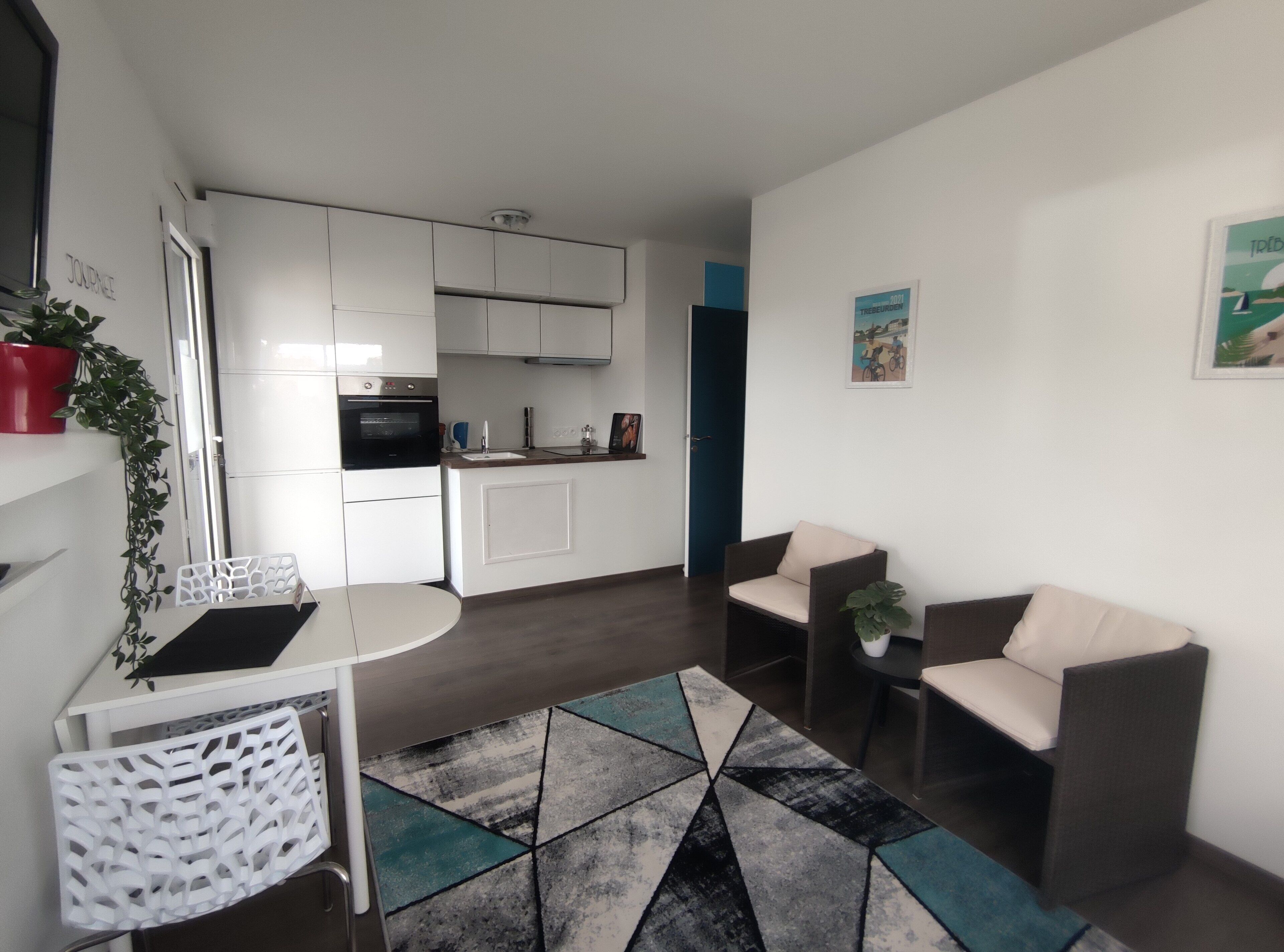 Un appartement moderne comprenant un coin cuisine, un espace repas et un salon avec deux canapés et une table basse.