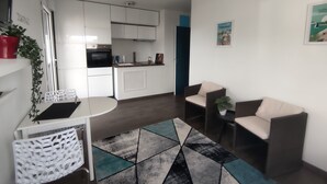Un appartement moderne comprenant un coin cuisine, un espace repas et un salon avec deux canapés et une table basse.