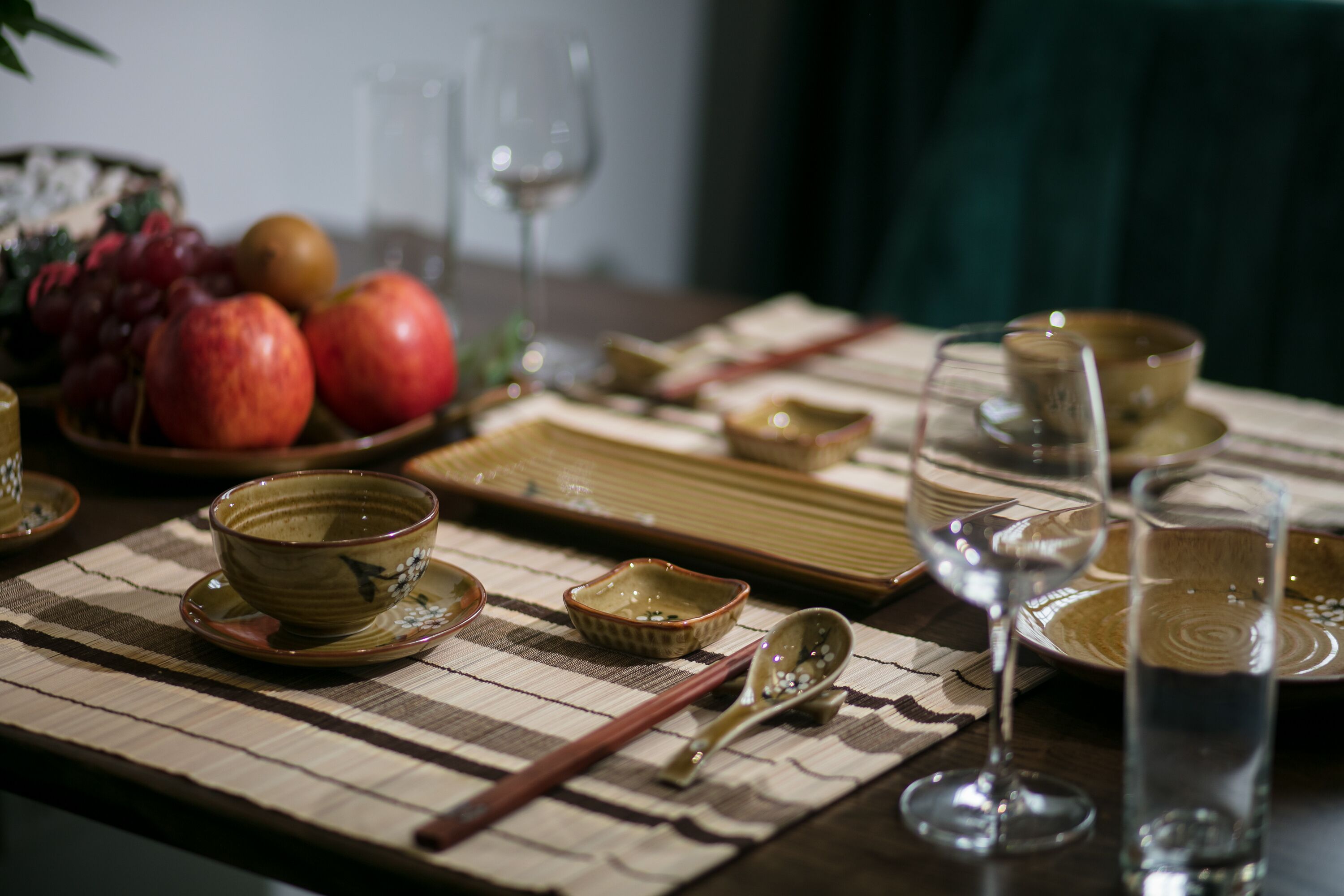Une table à manger dressée avec de la vaisselle traditionnelle d’Asie de l’Est, comprenant des bols, des baguettes et des verres.