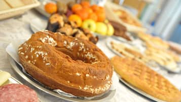 A table with various food items including a ring-shaped bread, pastries, and a selection of fruits and vegetables.