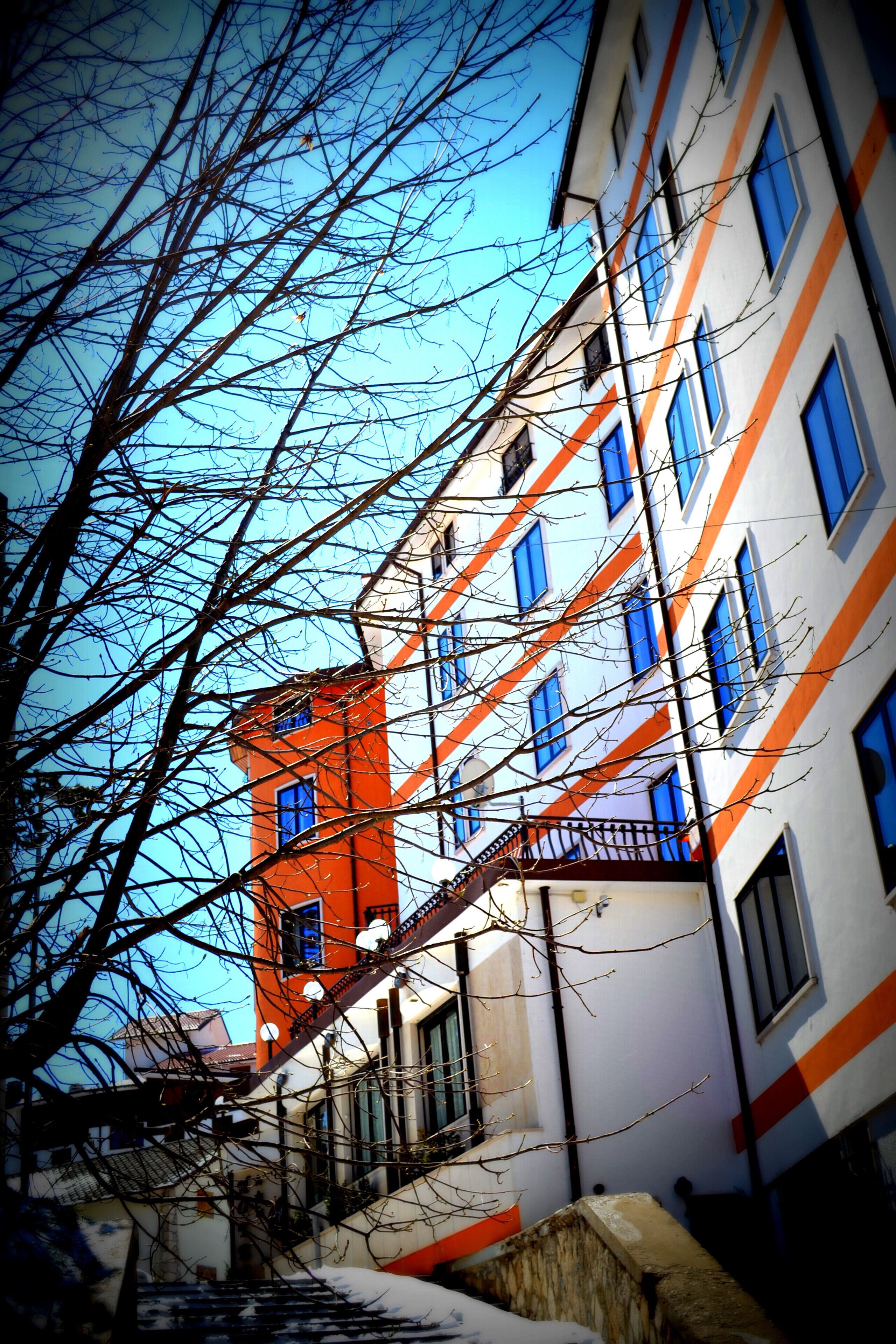 A multi-story building with a red and white facade, multiple windows, and a visible staircase.