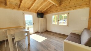 Una habitación con paneles de madera, una mesa de comedor, sillas, un sofá y un televisor montado en la pared.
