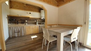Una cocina con armarios de madera, una mesa de comedor y sillas. Hay una ventana que proporciona luz natural.