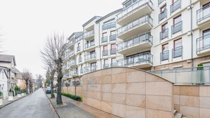 Un edificio de apartamentos moderno con balcones, una acera pavimentada y cielo despejado.