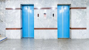 A modern elevator with blue doors and a marble wall with a red stripe. - Boonchai Mansion (Hat Yai)