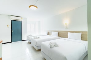A hotel room with three beds, a wooden headboard, white bedding, and a blue door. - Boonchai Mansion (Hat Yai)
