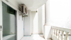 A balcony with a white railing, a sliding glass door, and an air conditioning unit mounted on the wall. - Boonchai Mansion (Hat Yai)