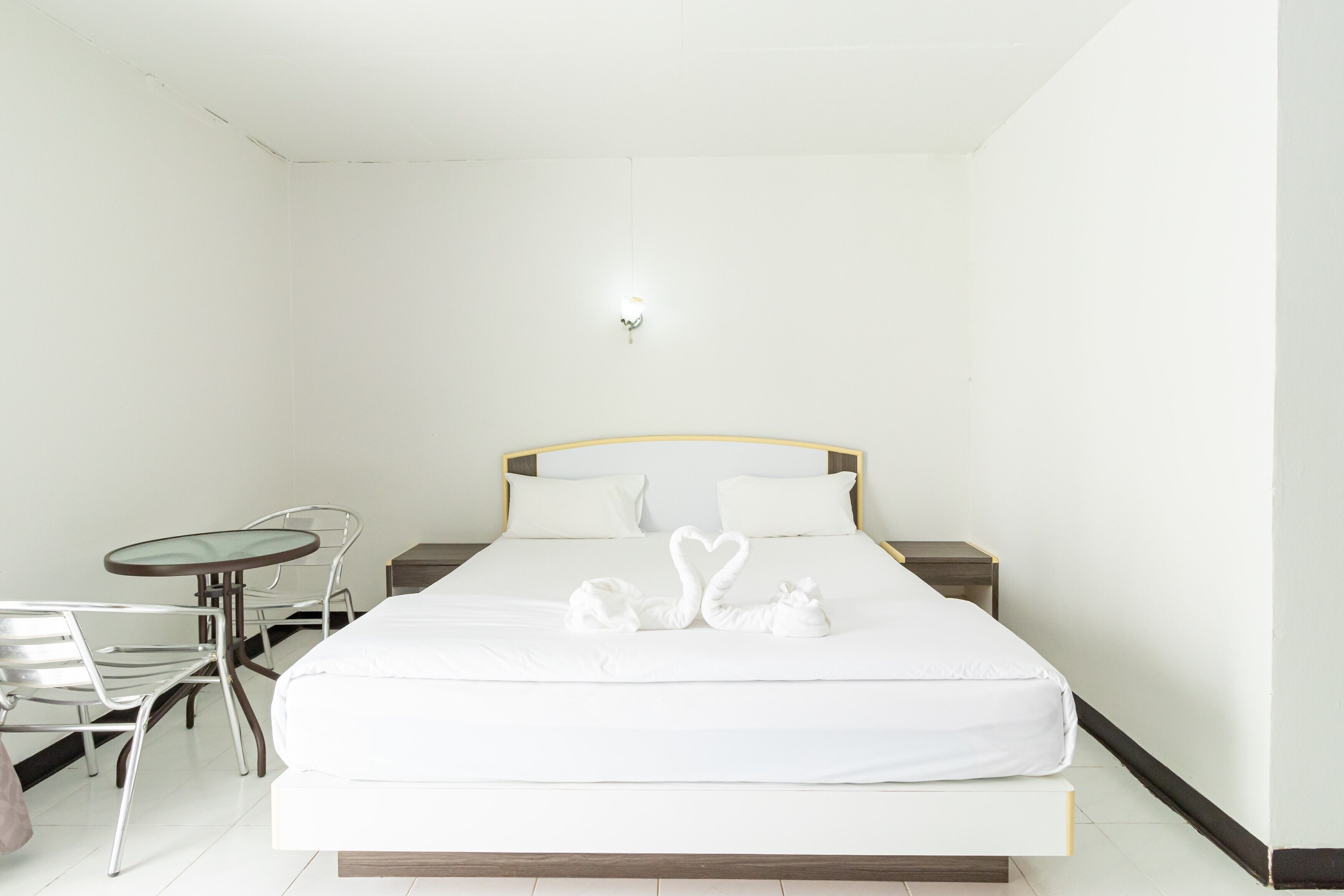 A hotel room with a bed, a small table, and two chairs.