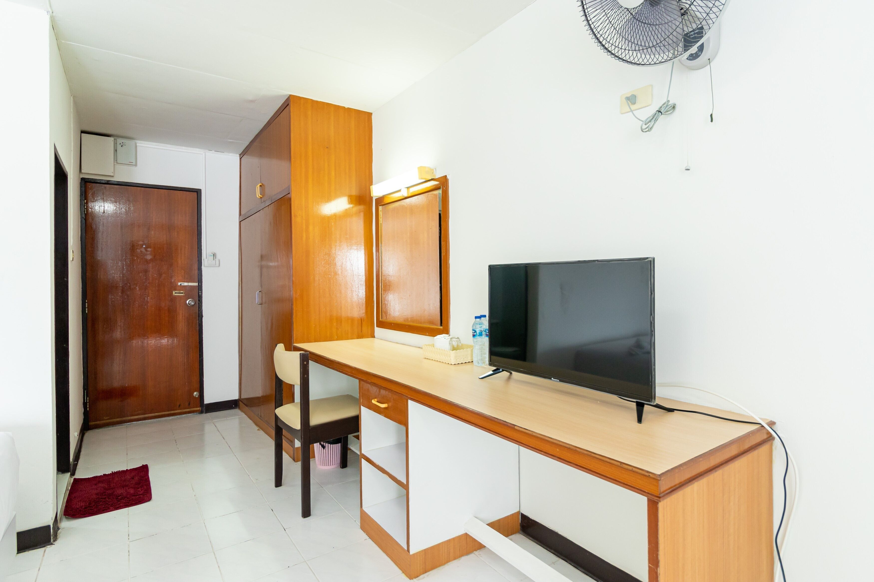A compact room with a wooden desk, a TV, a chair, and a wardrobe.