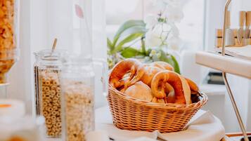 En morgenmadsopsætning med en fletkurv med brød, et glas med sugerør og en hvid dug.