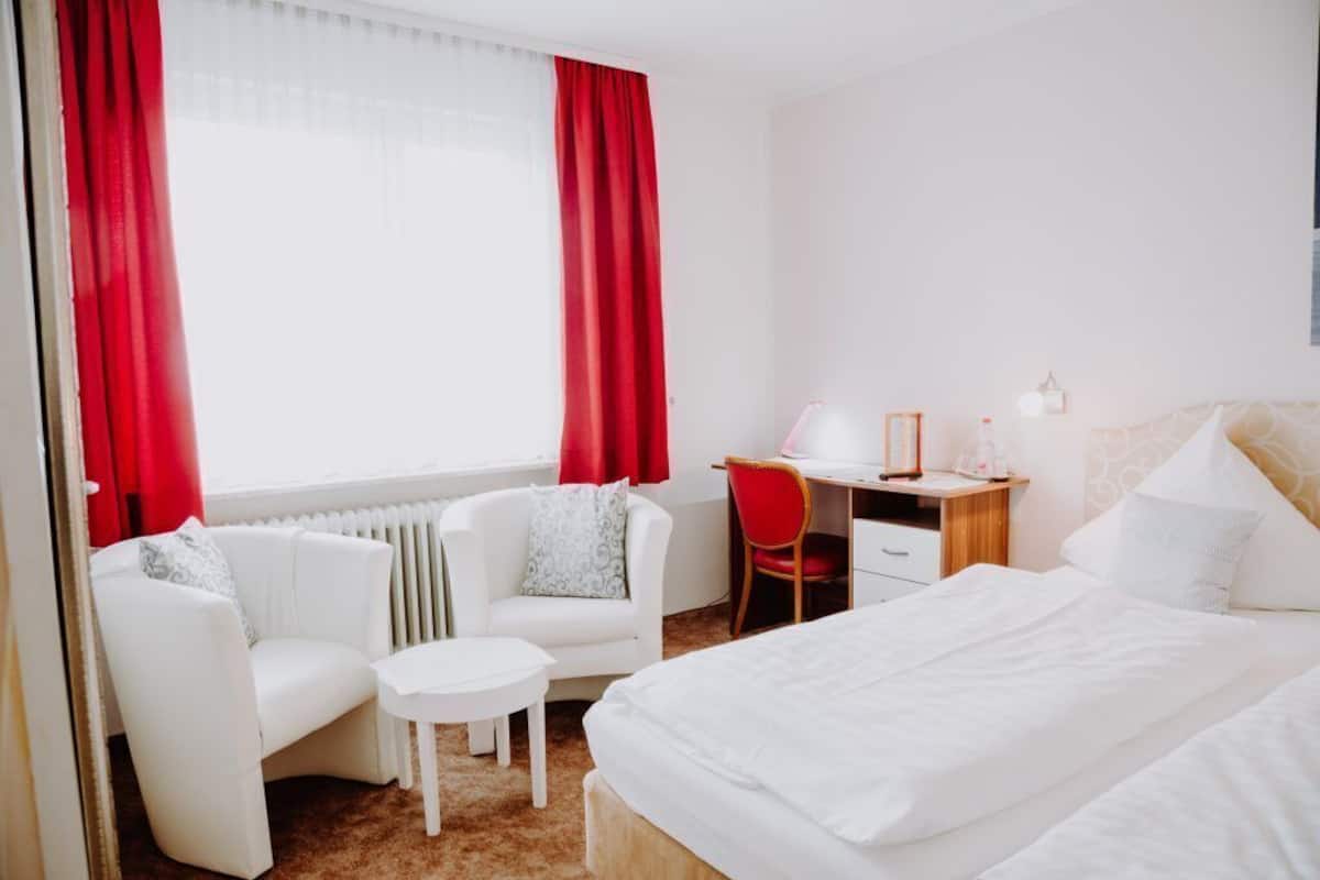 A hotel room with a bed, a desk, a chair, and a sofa.