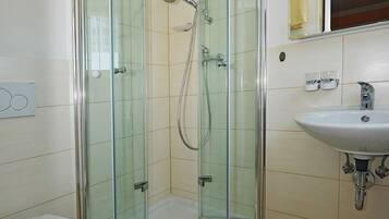 Une salle de bain moderne avec une douche à parois de verre, des toilettes blanches et un lavabo avec un miroir au-dessus.