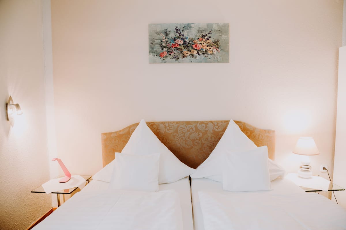 A hotel room with a bed, a nightstand, a lamp, and a painting on the wall.