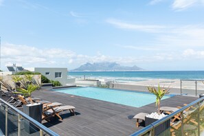 A rooftop pool with lounge chairs and a view of the ocean. - Infinity G4 (Cape Town)