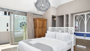 A modern bedroom with a large bed, a wooden wardrobe, and a decorative chandelier. - Pine Road 26 (Cape Town)