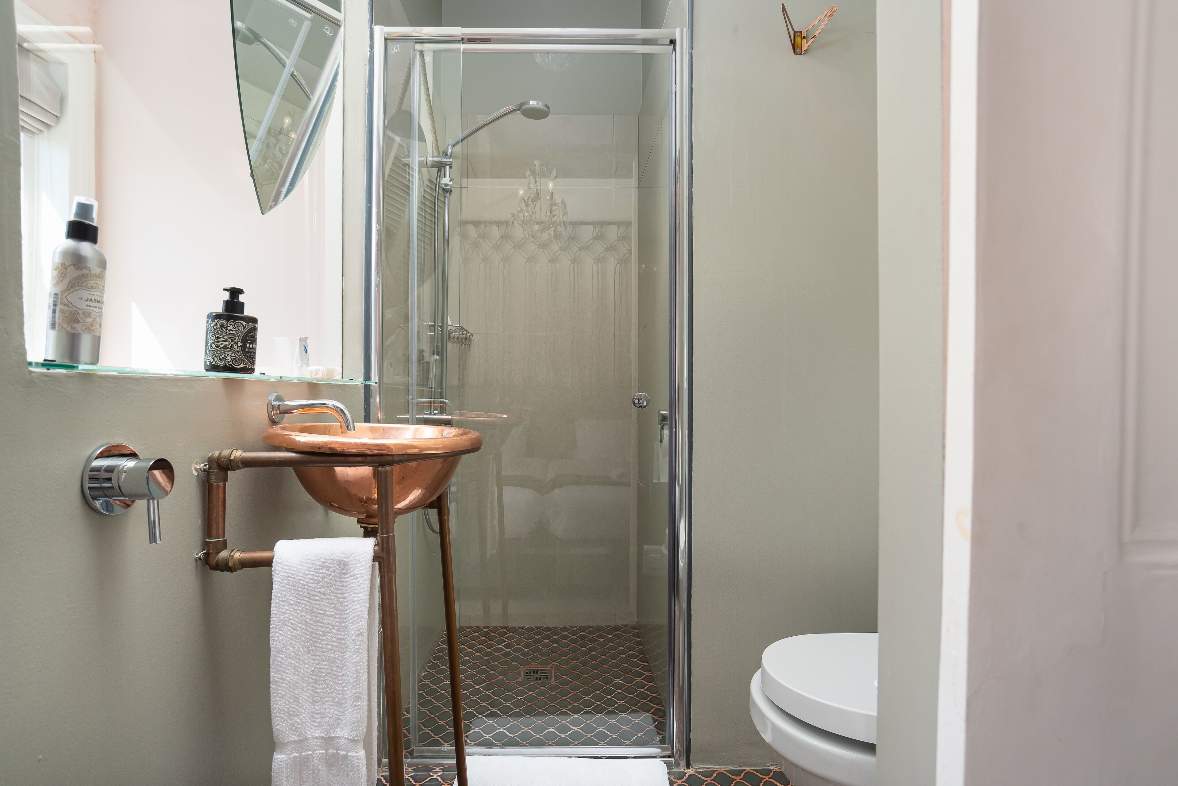Une salle de bain moderne avec une douche à parois de verre, un lavabo en cuivre et des toilettes blanches.