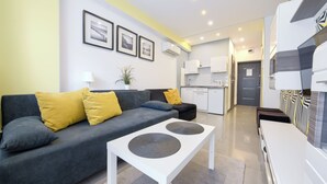 A modern living room with a grey sofa, yellow cushions, a white coffee table, and a kitchen area in the background. - Apartamenty Sun & Snow Nowa Slavia (Miedzyzdroje)