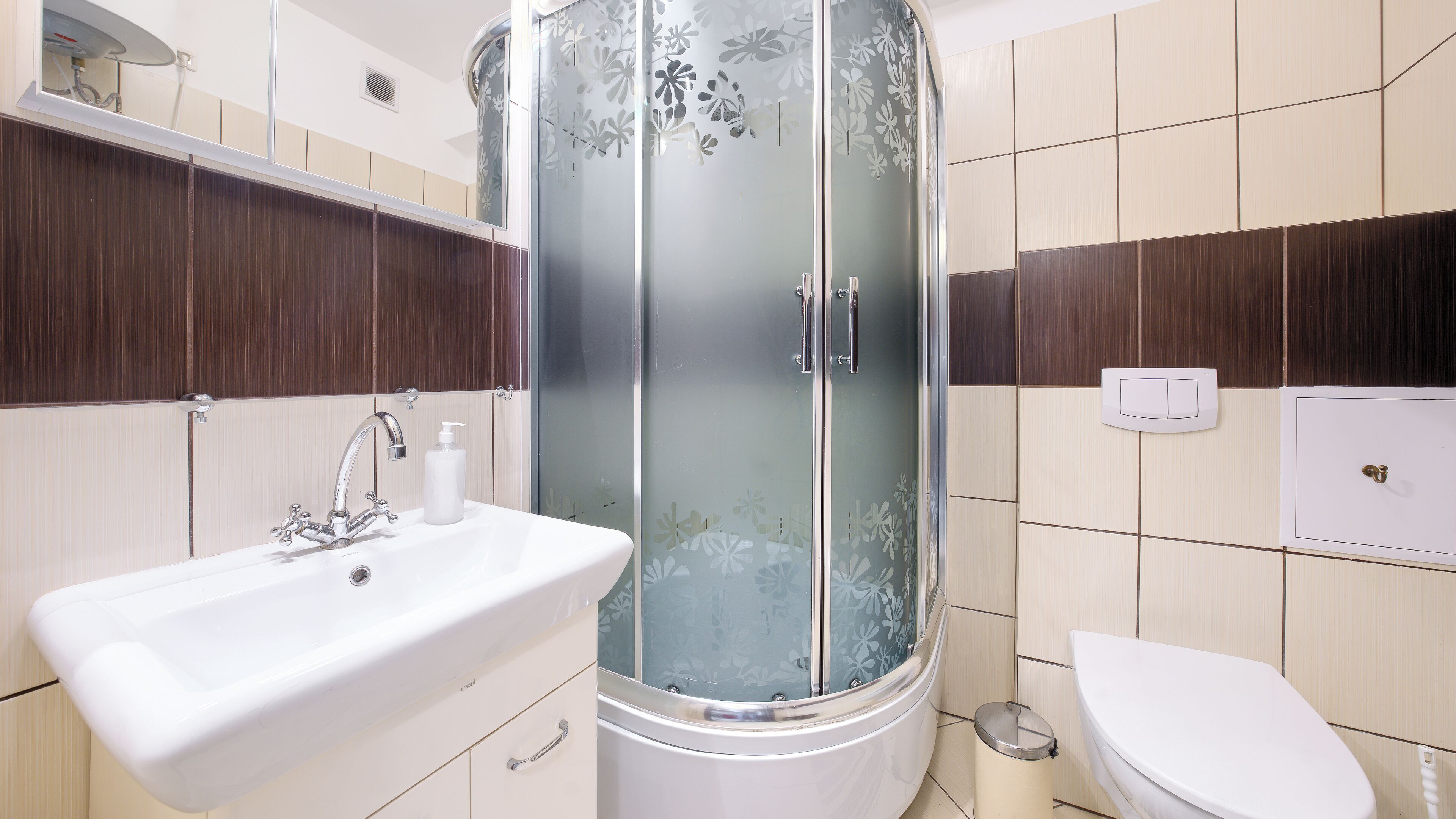 A modern bathroom with a shower, sink, and toilet.
