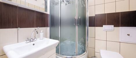 A modern bathroom with a shower, sink, and toilet.