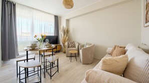 Un salon moderne comprenant un coin repas, un ensemble de canapés et un téléviseur.