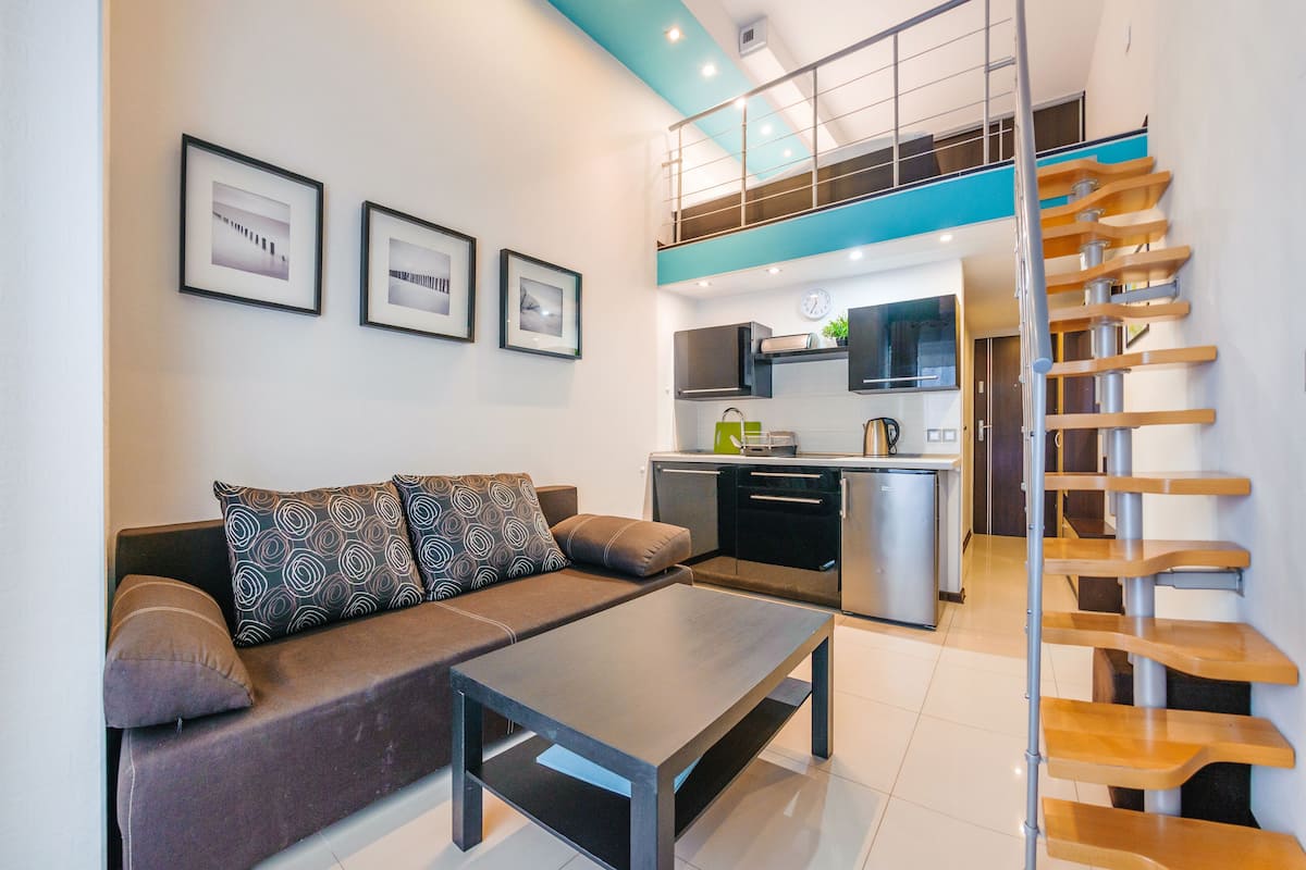 Una sala de estar moderna con un sofá, una mesa de centro y una escalera con escalones de madera.