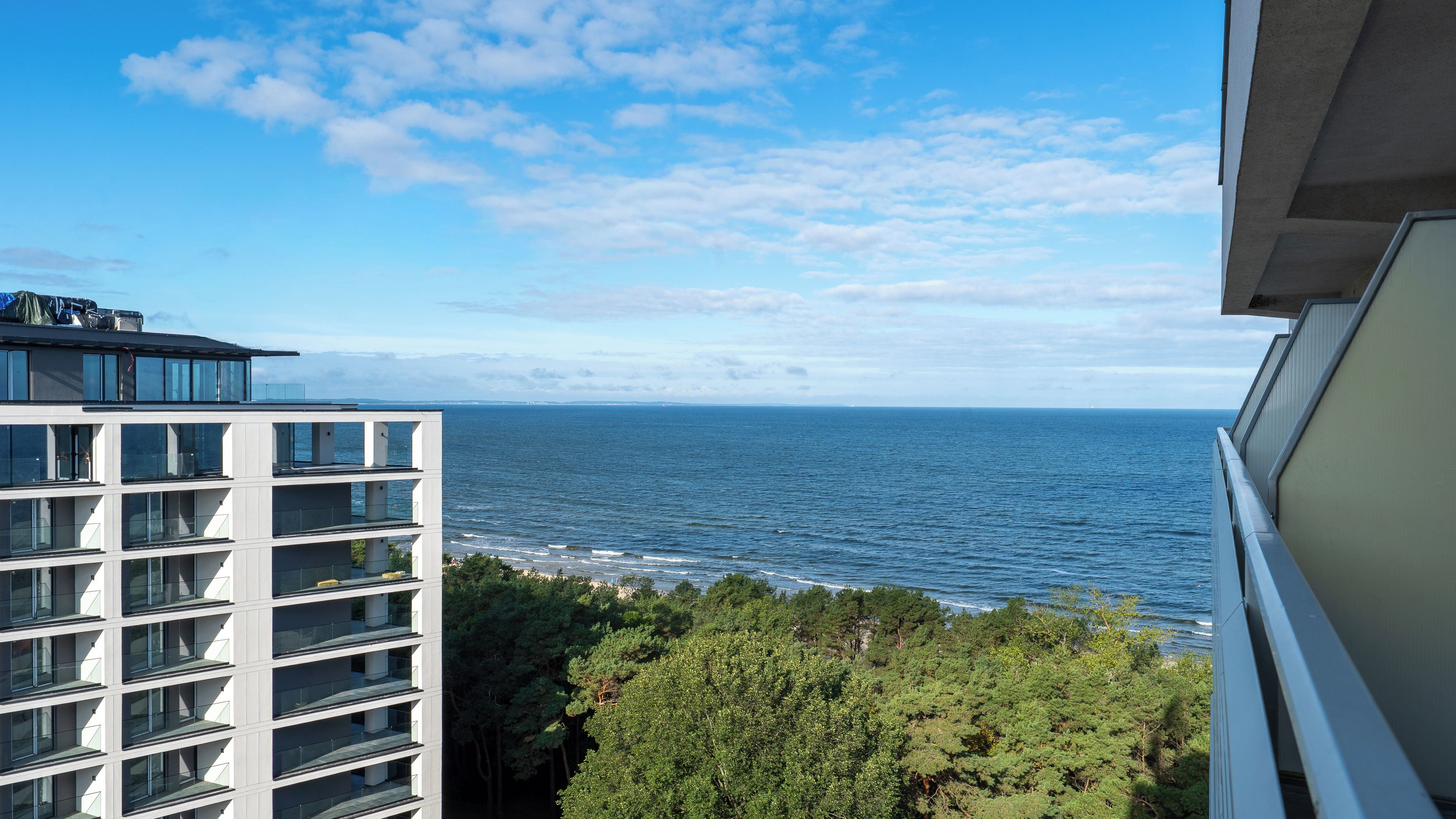 A high-rise building with multiple balconies overlooking a body of water.
