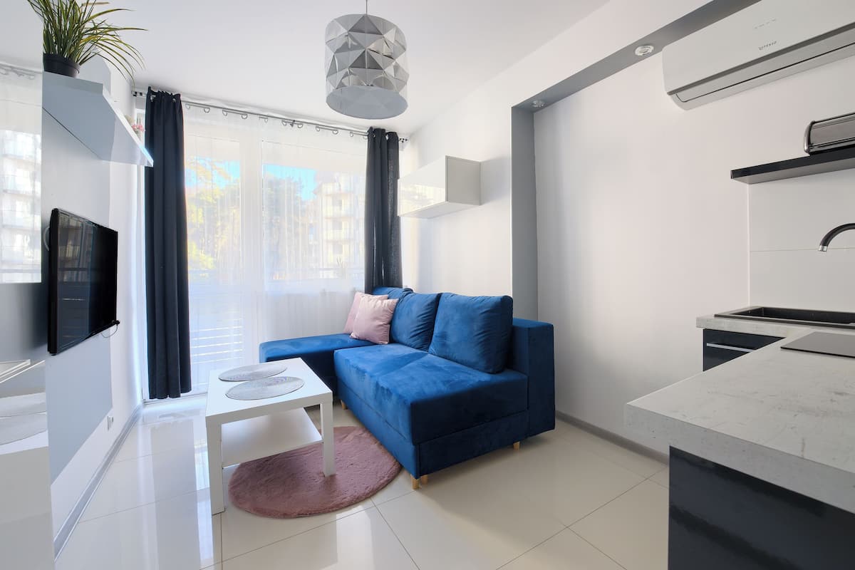 Un apartamento moderno con sala de estar, kitchenette y un amplio ventanal con cortinas.