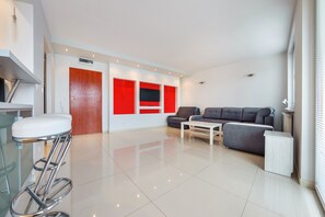 A modern living room with a grey sofa, a white coffee table, and a red accent wall. - Sun & Snow, Światowida (Miedzyzdroje)
