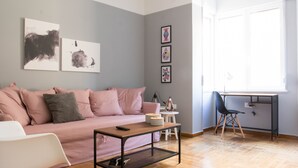 A modern living room with a pink sofa, a wooden coffee table, a black chair, and a desk with a computer. - UPSTREET Chic and Cosy Flat in Plaka (Athens)