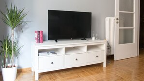 A white TV stand with a flat-screen TV, a potted plant, and a few books. - UPSTREET Chic and Cosy Flat in Plaka (Athens)