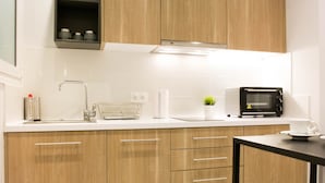 A modern kitchen with wooden cabinets, a stainless steel sink, a microwave, and a small potted plant. - UPSTREET Chic and Cosy Flat in Plaka (Athens)