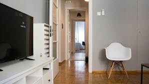 A modern living room with a flat-screen TV, white furniture, and a wooden floor. - UPSTREET Chic and Cosy Flat in Plaka (Athens)