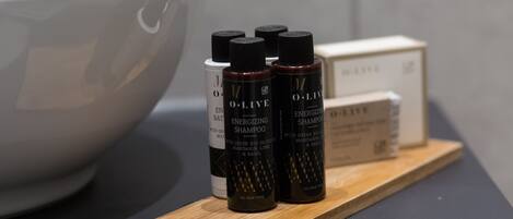 A wooden tray with three bottles of Energizing Shampoo and a white box on a dark surface.