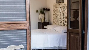 A room with a bed, a potted plant, a chair, and a table. - Alba e tramonto B&B (Mola di Bari)