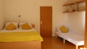 A bedroom with a bed, a bedside table, a chair, a door, and a shelf with items. - Beach Apartment Jakobus (Lumbarda)