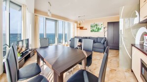 A modern living room with a dining area, large windows, and a view of the sea. - Sun & Snow Wechta - Promenada Gwiazd (Miedzyzdroje)