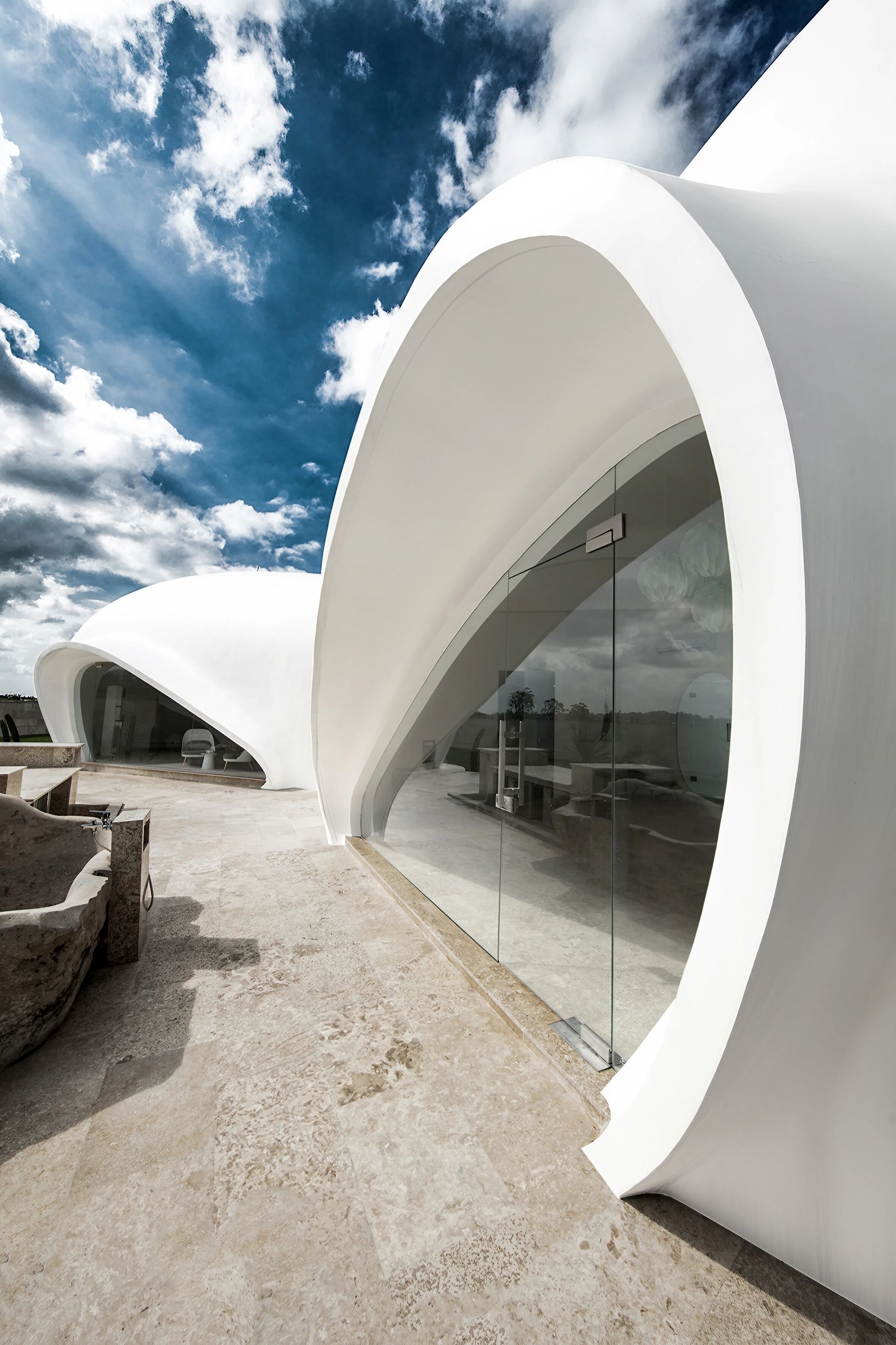 A modern architectural structure with curved white walls and a glass entrance.