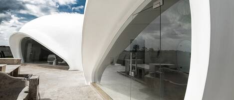 Una estructura arquitectónica moderna con paredes blancas curvas y una entrada de vidrio.