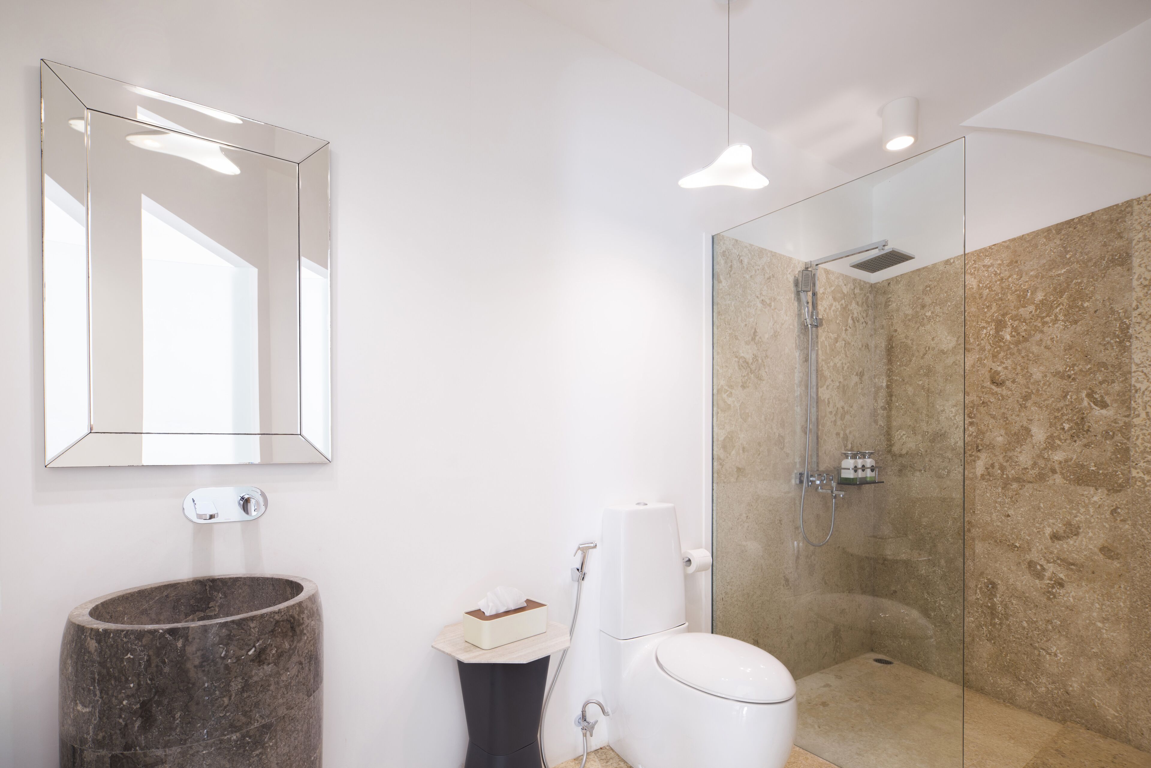 A modern bathroom with a marble sink, a toilet, a glass-enclosed shower, and a large mirror.
