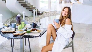 Un interior moderno con una escalera de caracol, una mesa de comedor dispuesta para el desayuno y una persona sentada.
