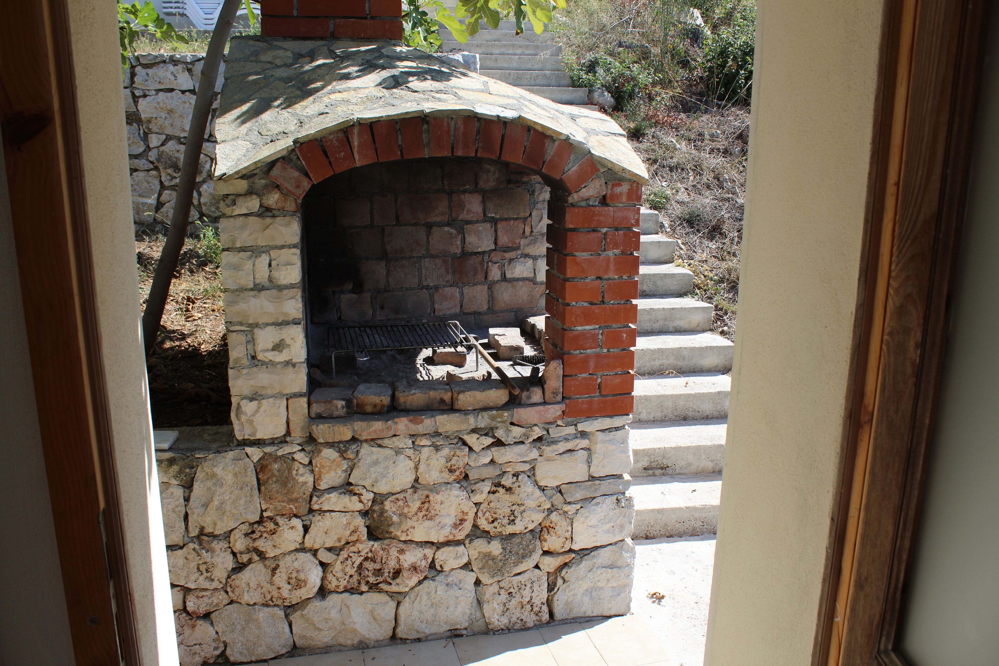Un horno de piedra al aire libre con un arco de ladrillo, situado en la parte inferior de una escalera de piedra.
