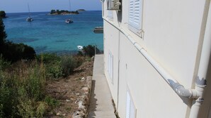 A coastal building with a narrow stone pathway leading to a balcony overlooking the sea. - Apartments Andrea (Vela Luka)